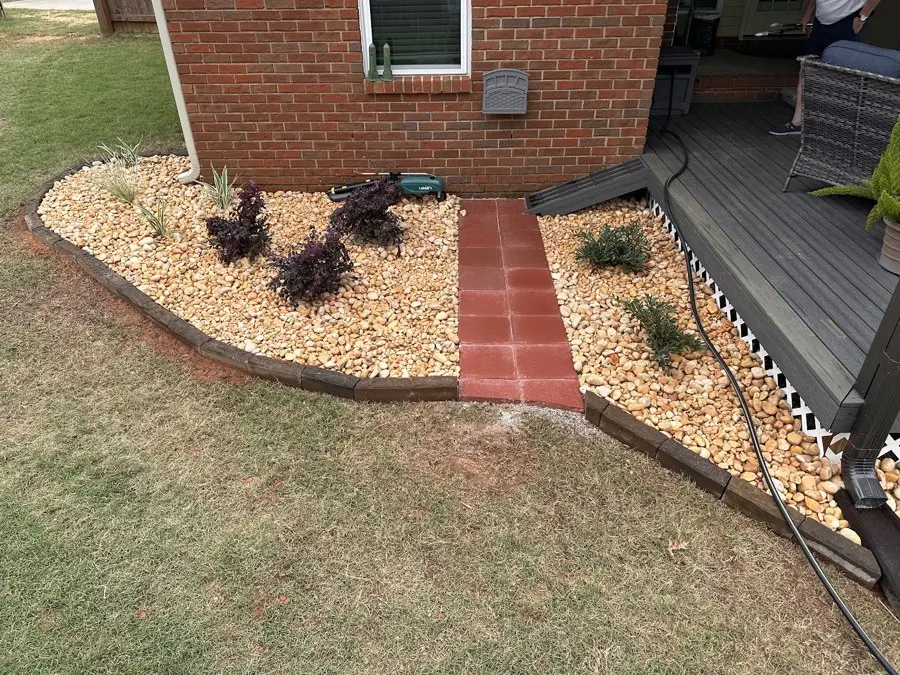 Stone bed with plants beside a brick house